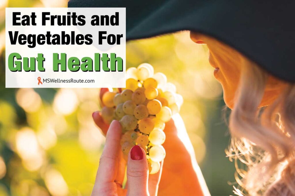 Woman wearing a hat looking at grapes with overlay: Eat Fruits and Vegetables for Gut Health