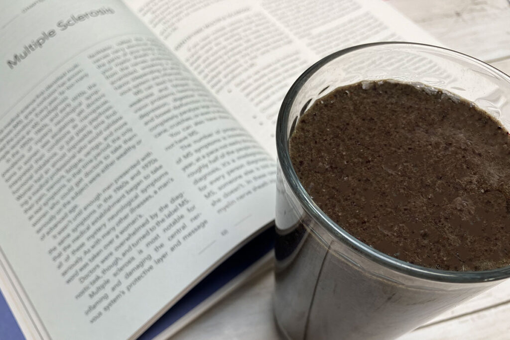 Medical Medium book open to multiple sclerosis pages with smoothie next to it.