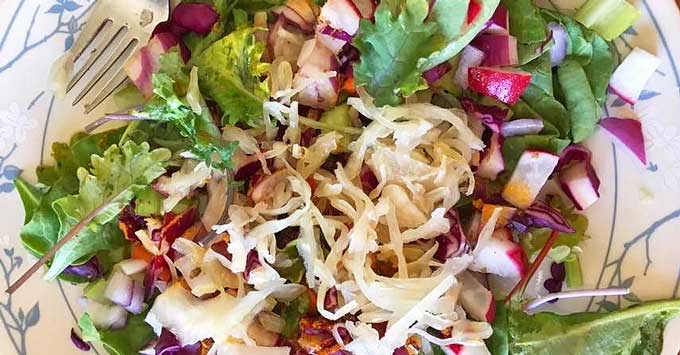 A nutrient-dense salad with sauerkraut on top.