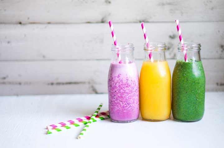 A purple, yellow, and green smoothie with straws.
