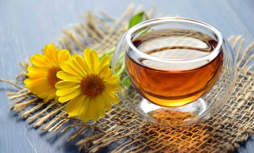 Wicker mat with yellow flowers and herbal tea.