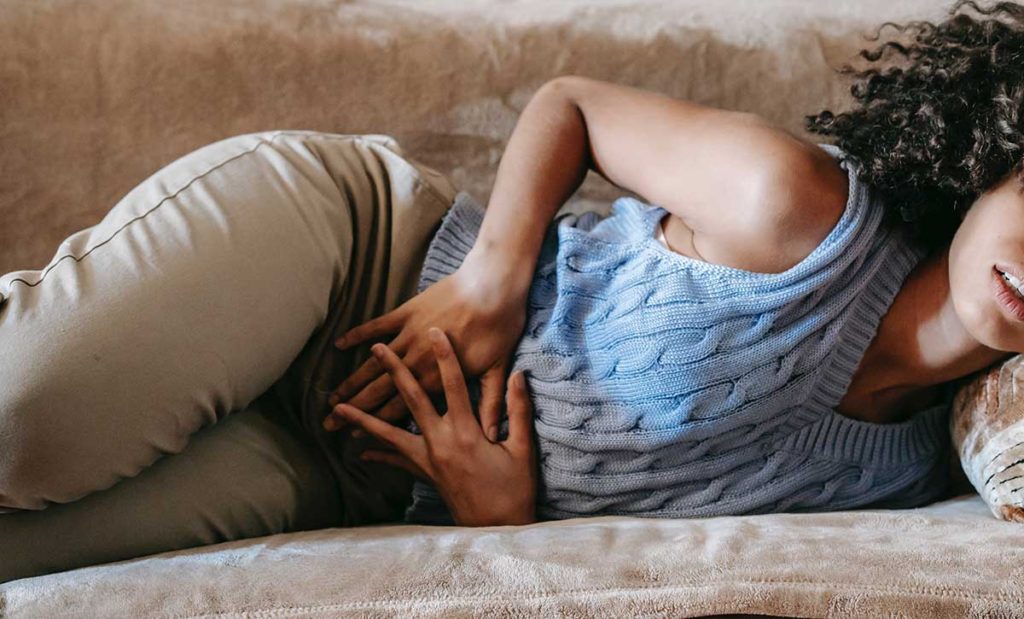 Young woman laying down holding stomach.