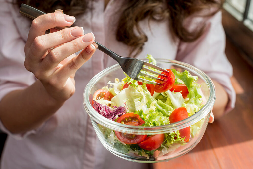 Brunette woman eating a salad.