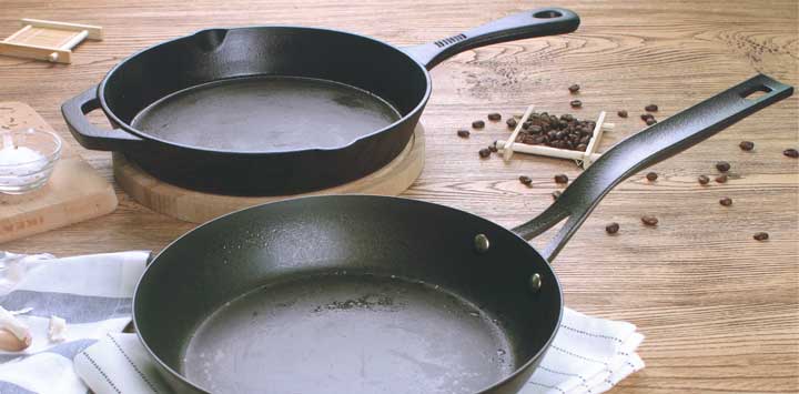 Two cast iron skillets with peppercorns on table.