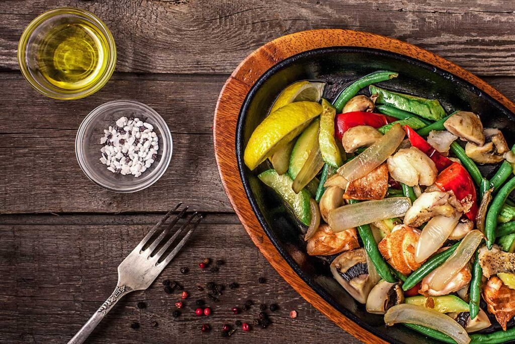 Vegetables with chicken dinner on dark wooden table.