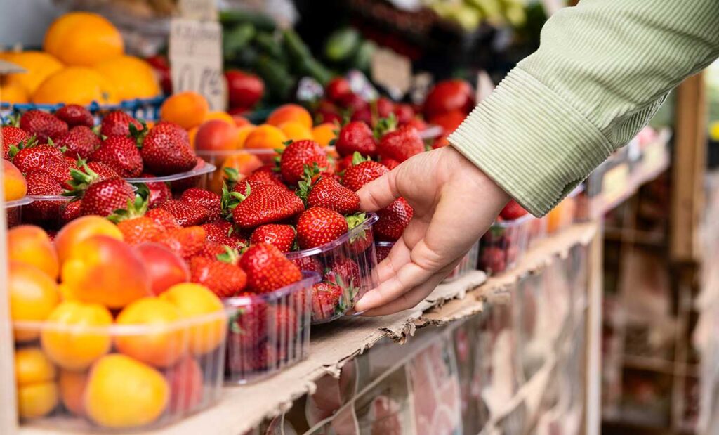 Close up of a woman's hand holding strawberries at the market.