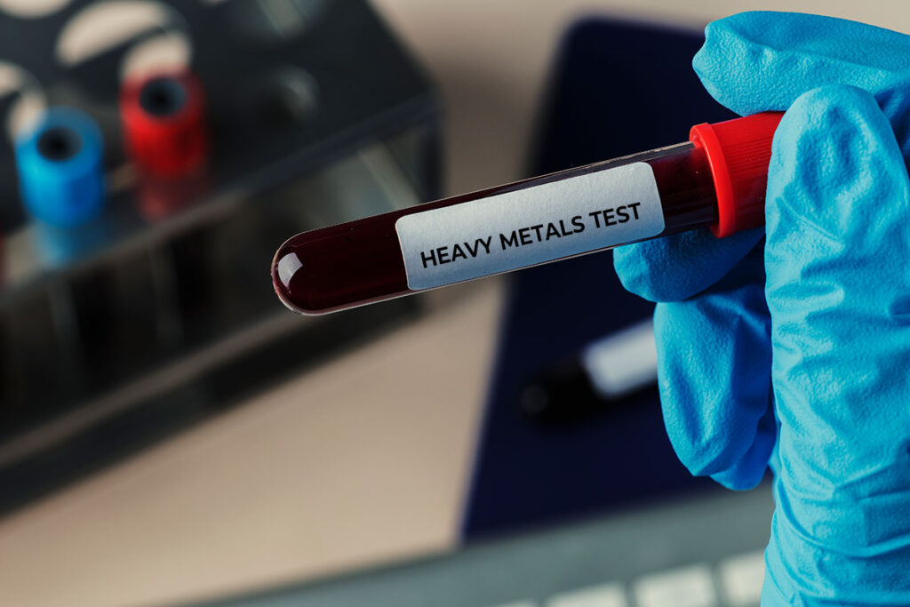 Close up of health care providers hand with blue glove holding a blood tube sample.