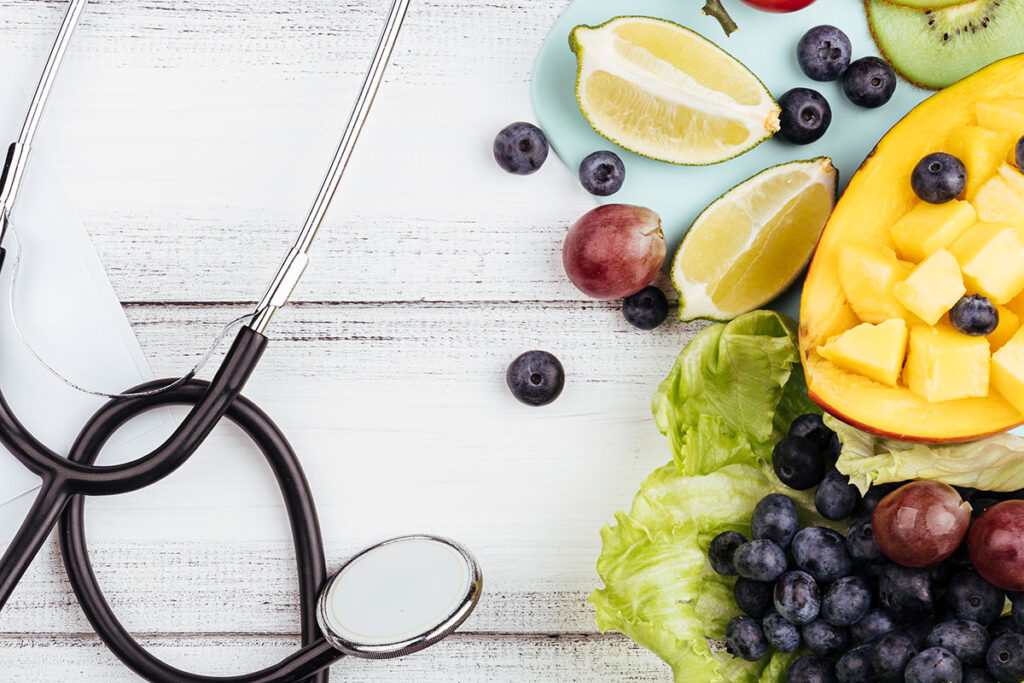Fruit on lettuce with stethoscope and wooden background.