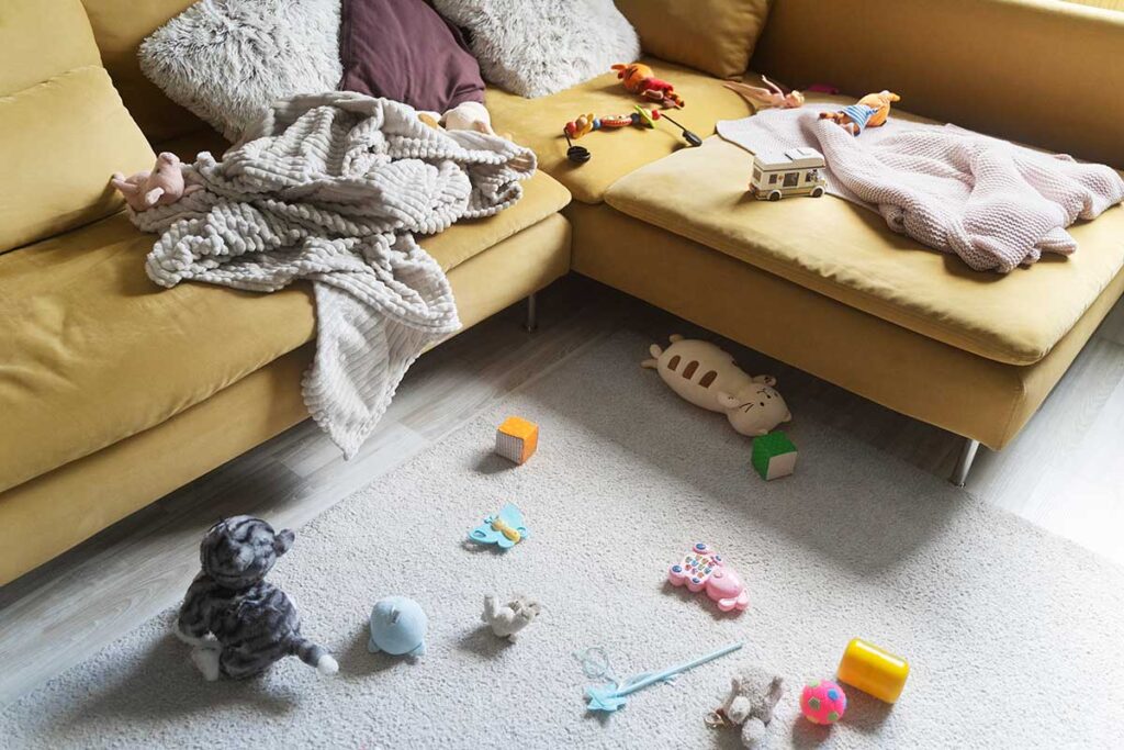 Messy living room with blankets and toys.