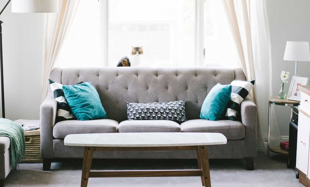 Living room with grey sofa, colorful pillows, and end table.