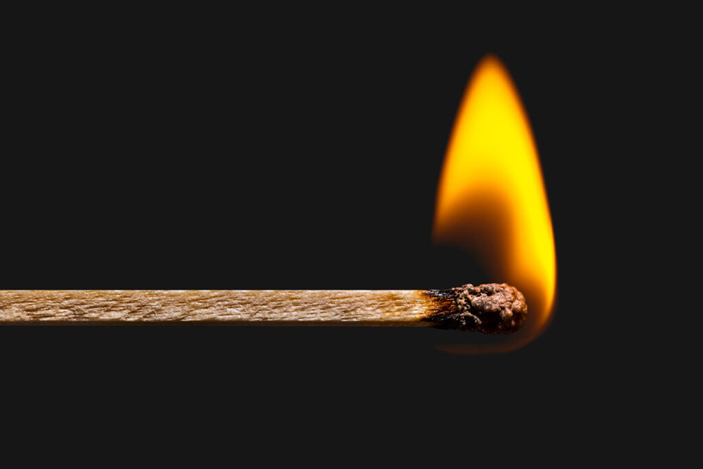A lit match with black background.