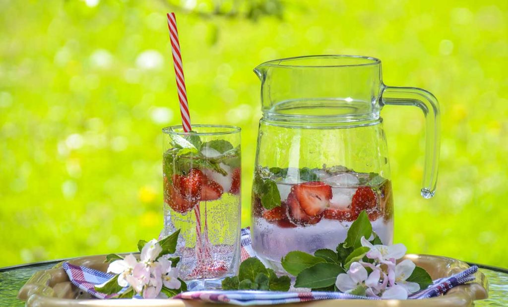 Pitcher of water and strawberries with glass