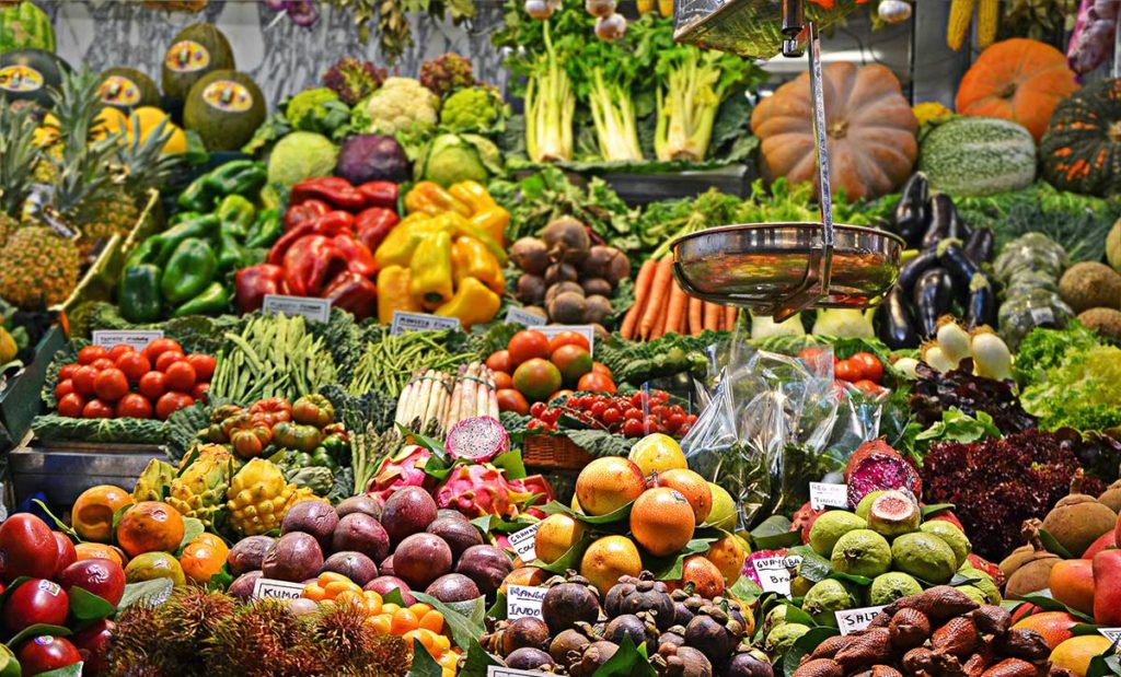 Produce market with many fruits and vegetables and scale.