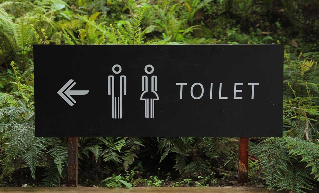 Outdoor toilet sign with gender symbols.