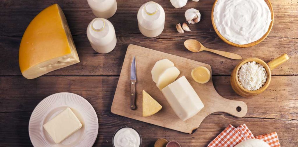 Variety of dairy products laid on a wooden table background.