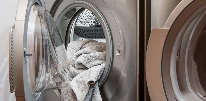 Open washing machine with towels hanging out.