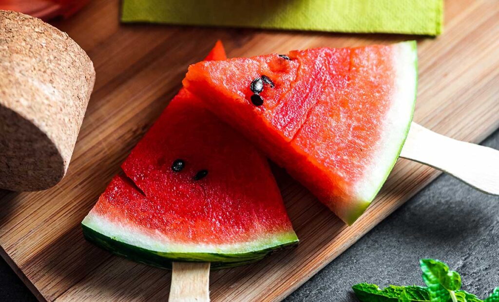 Two watermelon slices on a popsicle stick.