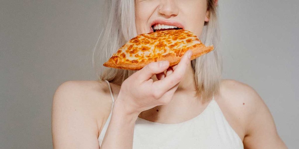 Blond woman eating pizza.