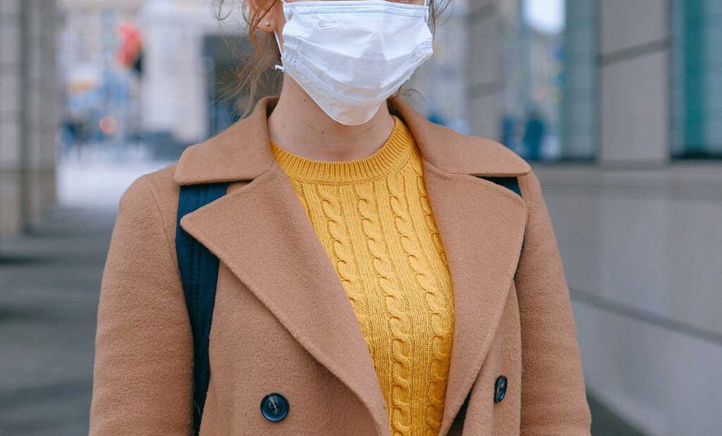 Woman in coat wearing a face mask.