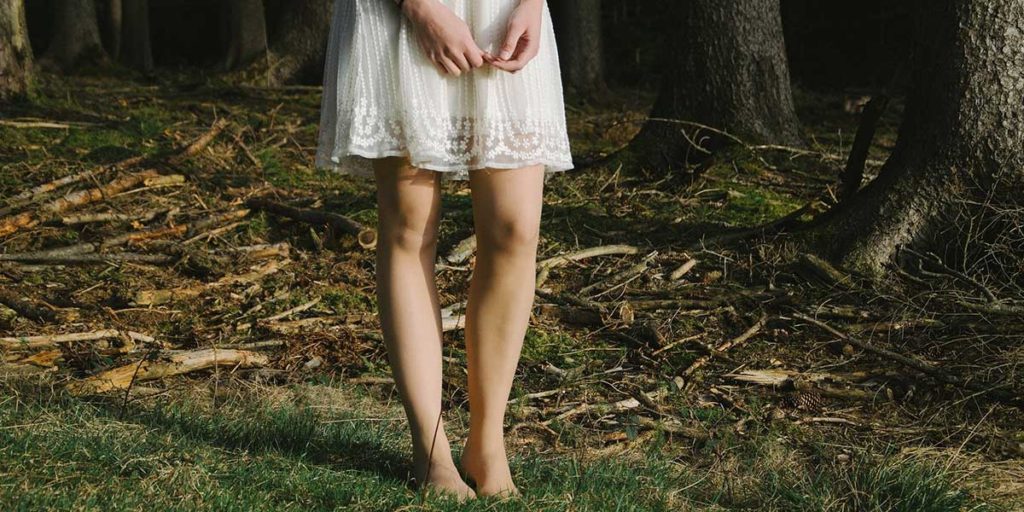 Woman in white sundress in forest. 