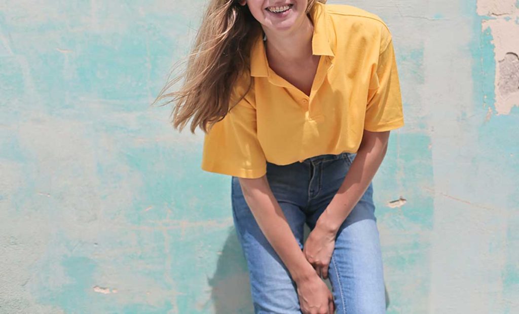 Young woman in bright yellow shirt and jeans.